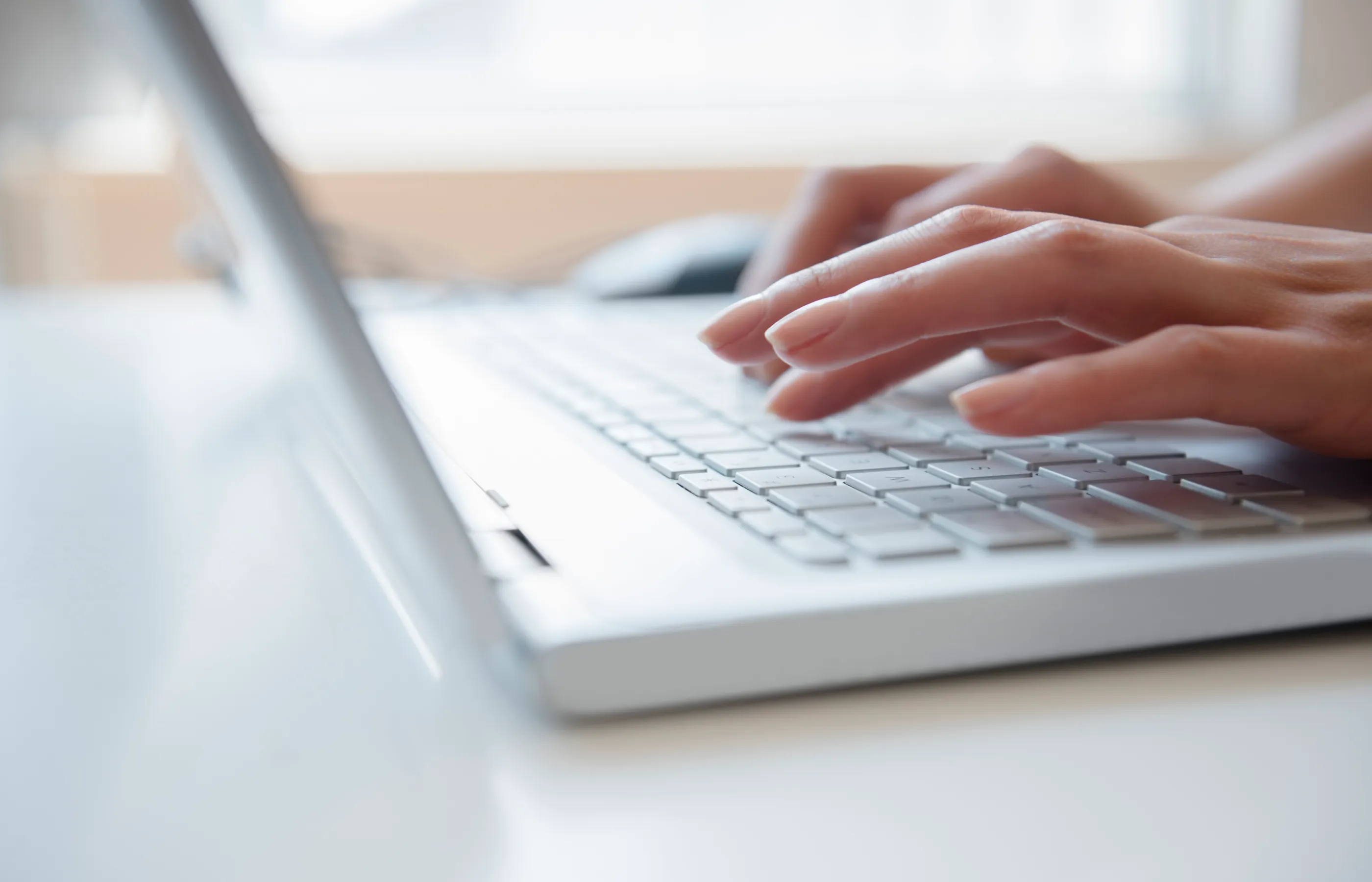 close-up of hands typing on a computer