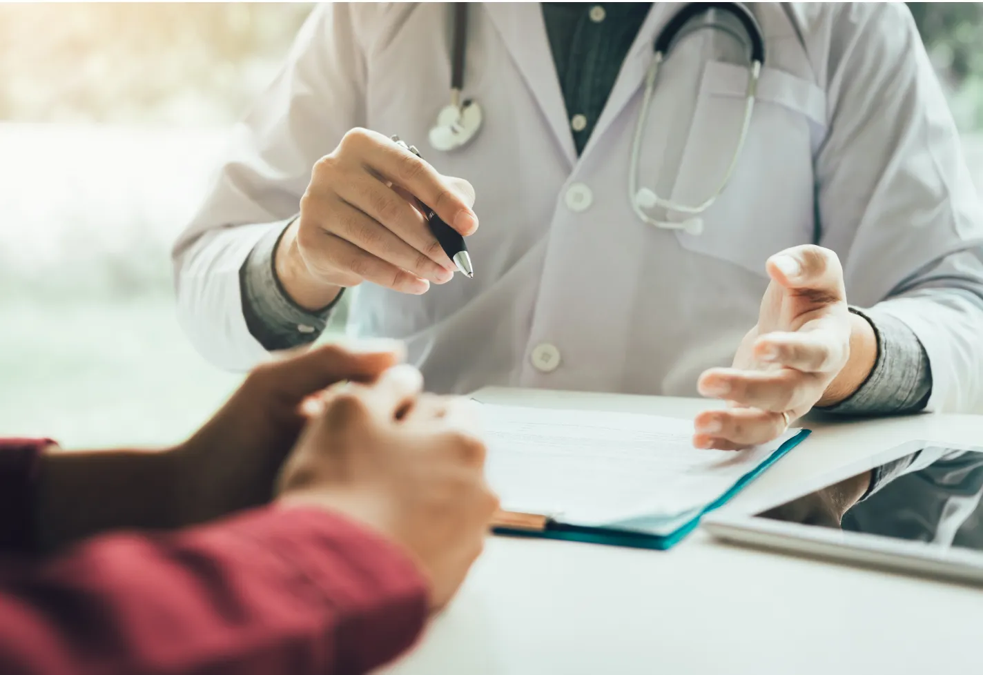 Hands of a patient and provider as they discuss clinical results and forms. 